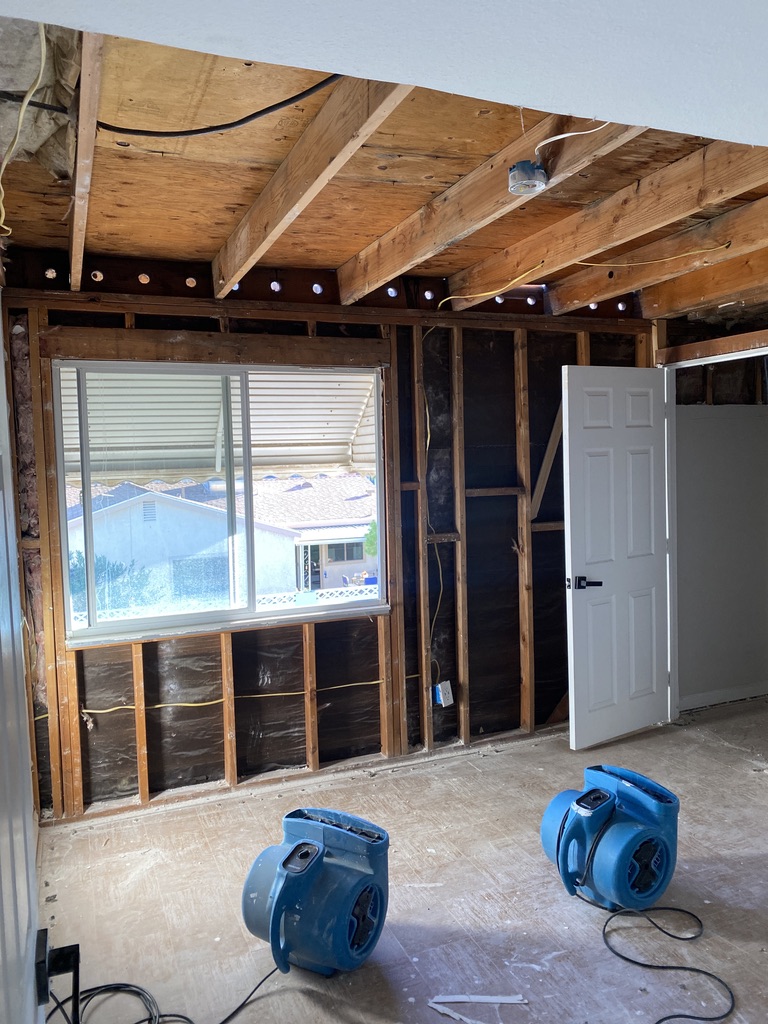 water damage service areas: air movers drying a room with exposed framing
