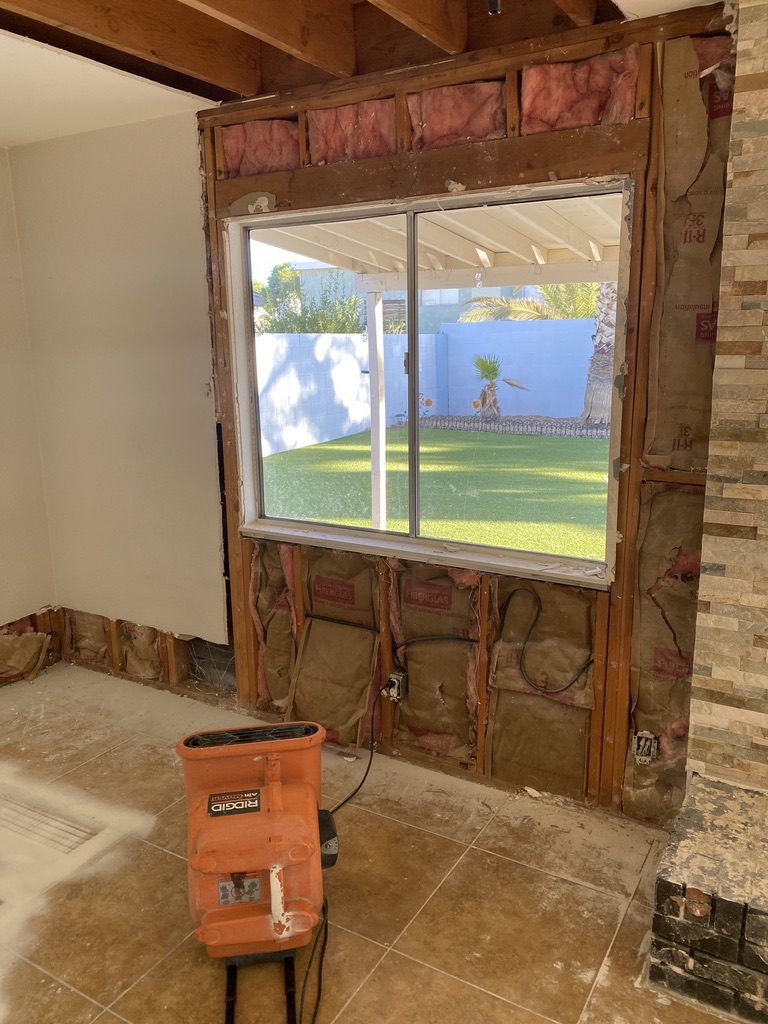 Orange air mover beside exposed wall studs and insulation