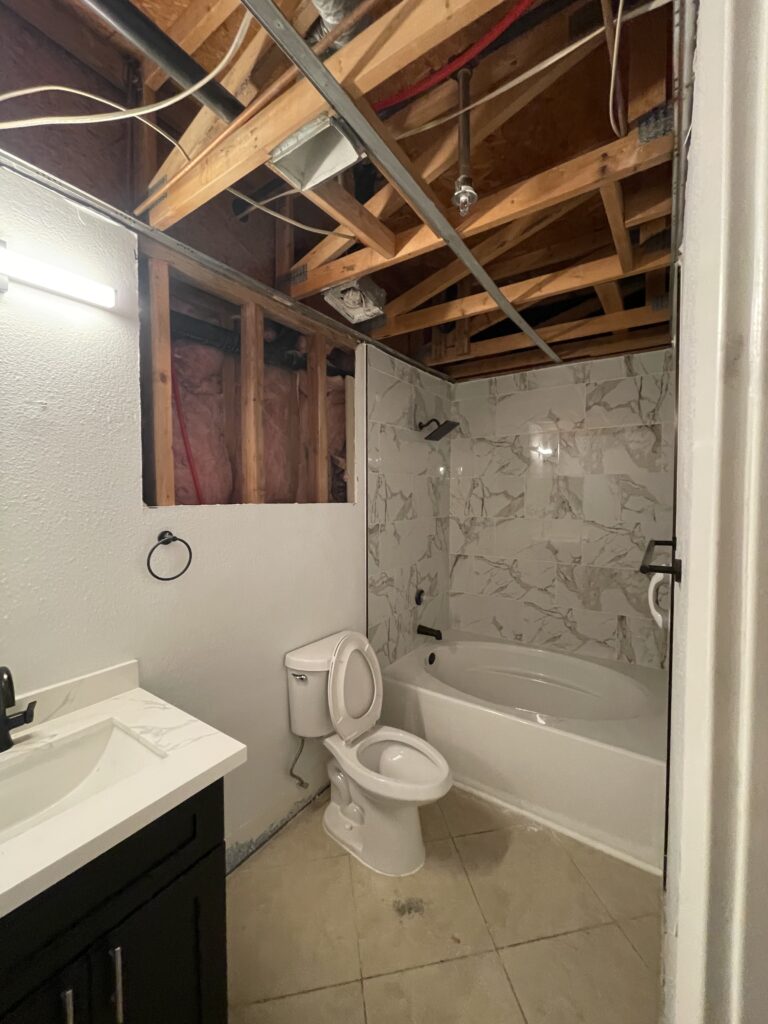 Las Vegas condo bathroom with ceiling and wall drywall removed, exposing framing during water damage restoration